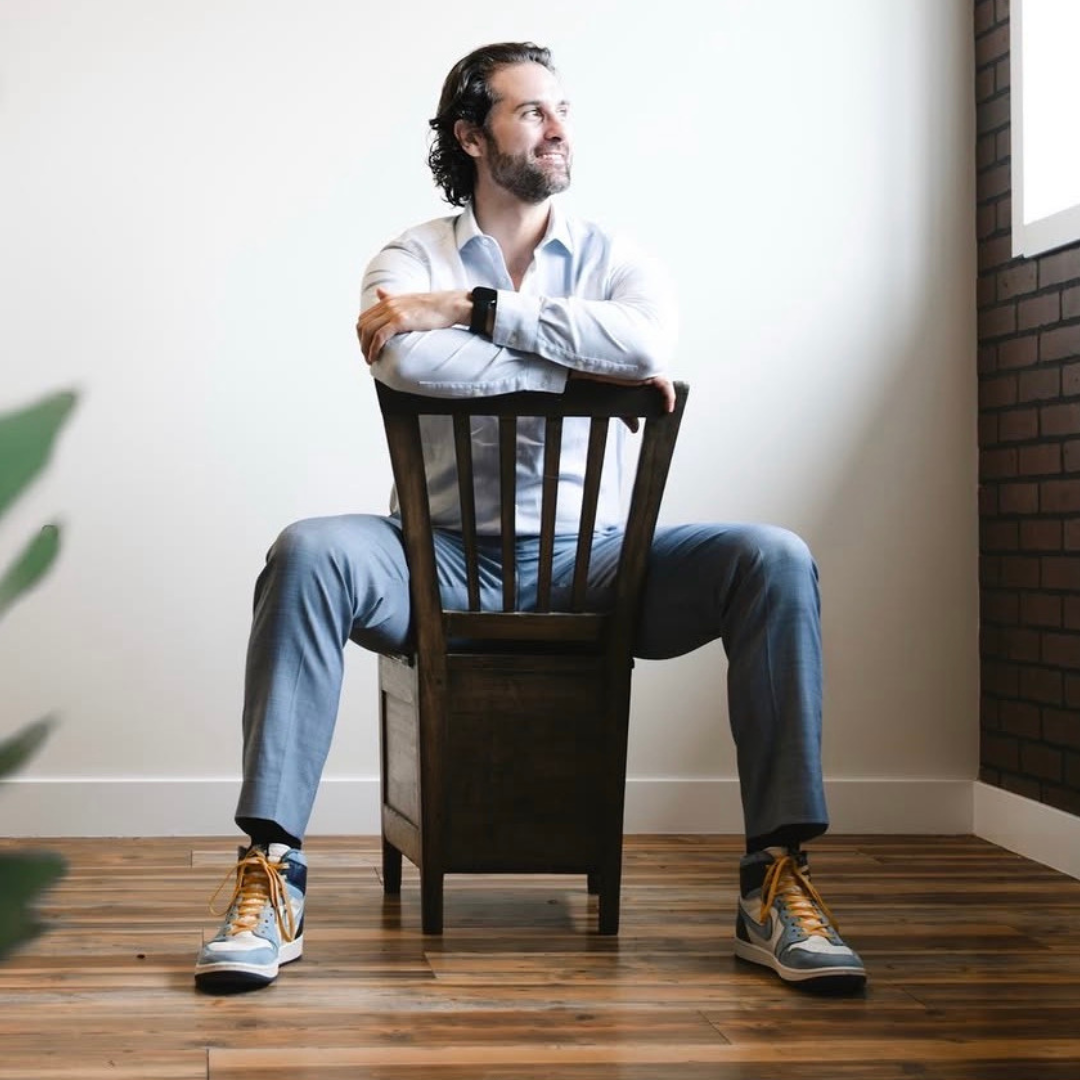 Alex Mackenzie seated backwards on a chair and looking toward a window